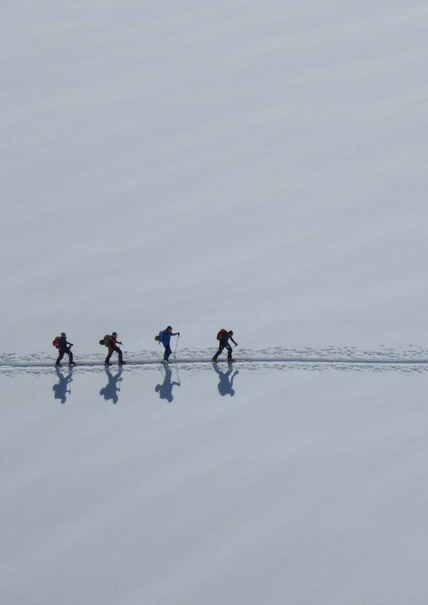 3 person in red shirt and black pants standing on snow covered ground during daytime